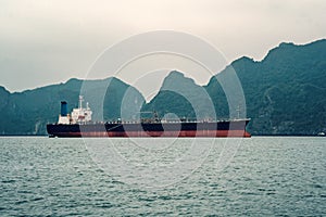 Big tanker anchored in Bay. A large transport ship in the sea against the background of high rocks. Vietnam