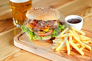 Big tasty burger and fries with beer on backround on the wooden table
