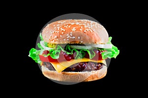 Big tasty hamburger or cheeseburger isolated on black background with grilled meat, cheese, tomato, bacon, onion. Burger