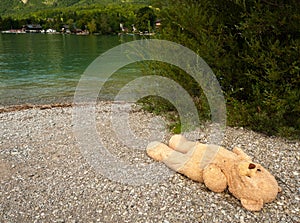 Big teddy bear lying on the shore of lake Wolfgangsee