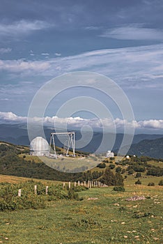 Big telescope alt-azimuthal at the day with mountains