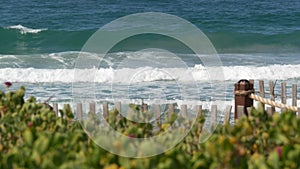 Big tide waves on beach, California shoreline USA. Pacific ocean coast, picket fence on sea shore.