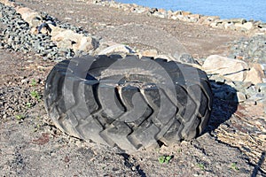 Big tire on a beach. Tractor and tire. Environnement and pollution. photo