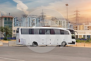 Big tourist buse on parking waiting for passengers on the city street against the backdrop of multi-storey buildings