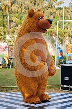 Big toy brown teddy bear stay in backyard, large brown bear costume of children party entertainer