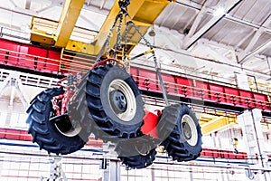 Big tractor wheels installation at assembly room at industrial plant