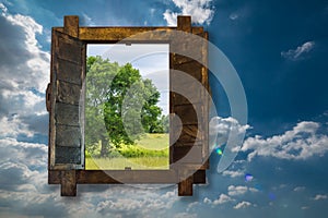 Big tree by looking through woonden window on blue sky