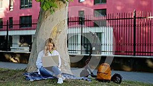 Beside of a big tree two students Afro American guy and blonde hair lady spending time they have a friendly conversation