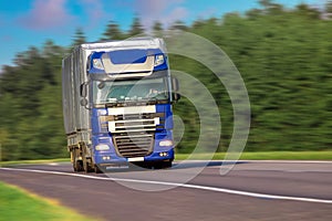 Big truck driving on the asphalt road in rural landscape. Cargo transportation concept