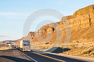 A big truck driving in the sunset with mountain background.
