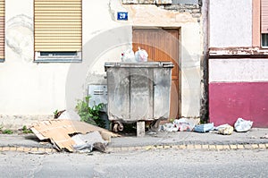 Big two metal dumpster garbage cans full of overflow litter polluting the street in the city with junk