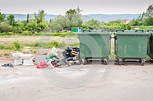 Big two metal dumpster garbage cans full of overflow litter polluting the street in the city with junk