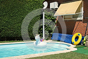 Big unicorn inflatable ring in a swimming pool at a house