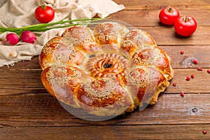 Big Uzbek bread from tandoor with raisin on brown wooden table with vegetalbes side view photo