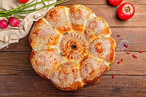 Big Uzbek bread from tandoor with raisin on brown wooden table with vegetalbes top view photo