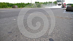 Big vehicle washing new asphalt road with water splashing. Car with washing tank spraying water to road after roadwork