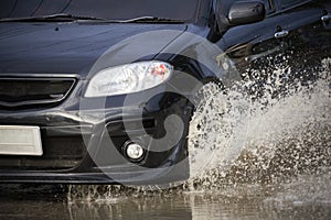 Big water splash with car on flooded road after rains