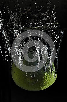 Big water splash from lime dropping in water.