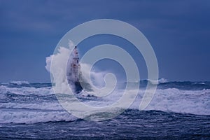 Big wave against old Lighthouse in the port of Ahtopol, Black Sea, Bulgaria on a moody stormy day. Danger, dramatic scene.