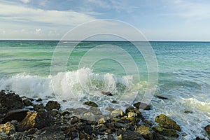 Big wave in Caribbean sea is breaking the coast. Turquoise sea water and blue sky. Eagle Beach of Aruba Island.