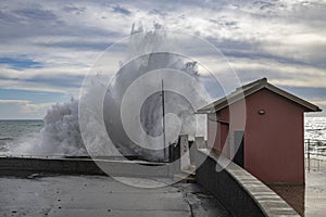 A big wave near a small house in a cloudy day with rough sea in Genoa, Italy