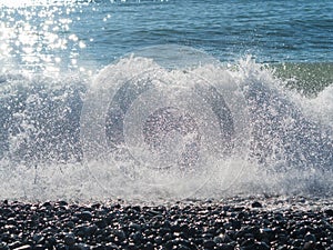 Big wave with water splashing in sunlight on the beach