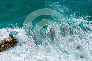 Big waves breaking on the shore. Waves and white foam. Coastal stones. View from above. The marine background is green