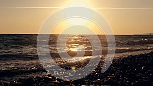 Big waves on a sea beach at sunset. Beautiful waves of slow motion video on the background of the orange sun