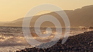 Big waves on a sea beach at sunset. Beautiful waves of slow motion video on the background of the orange sun