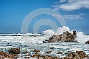 Big waves splashing and breaking on the coastline. Turbulent sea with rough tides from strong winds crashing onto beach