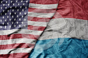 big waving colorful flag of united states of america and national flag of luxembourg on the dollar money background. finance