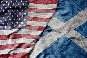 big waving colorful flag of united states of america and national flag of scotland on the dollar money background. finance concept