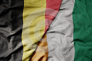 big waving national colorful flag of belgium and national flag of cote divoire