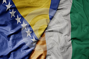 big waving national colorful flag of cote divoire and national flag of bosnia and herzegovina