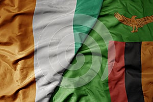 big waving national colorful flag of cote divoire and national flag of zambia