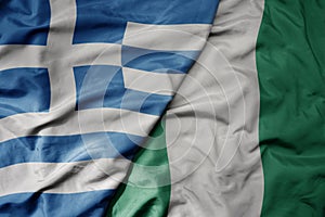 big waving national colorful flag of greece and national flag of nigeria