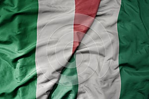 big waving national colorful flag of italy and national flag of nigeria