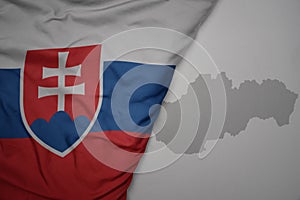 Veľká vlajúca národná farebná vlajka a mapa slovenska na sivom pozadí