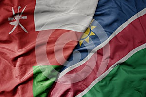 big waving national colorful flag of namibia and national flag of oman