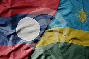big waving national colorful flag of rwanda and national flag of laos