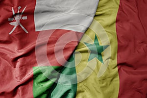 big waving national colorful flag of senegal and national flag of oman
