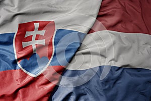 Big waving national colorful flag of slovakia and national flag of netherlands