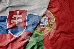 Big waving national colorful flag of slovakia and national flag of portugal