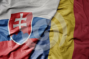 Big waving national colorful flag of slovakia and national flag of romania