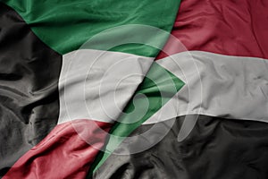 big waving national colorful flag of sudan and national flag of kuwait