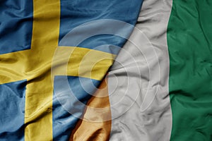 big waving national colorful flag of sweden and national flag of cote divoire