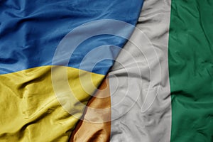 big waving national colorful flag of ukraine and national flag of cote divoire
