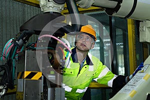 A big welding robot is being inspected and controlled by a robotics engineer.