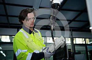 A big welding robot is being inspected and controlled by a robotics engineer.