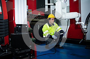 A big welding robot is being inspected and controlled by a robotics engineer.